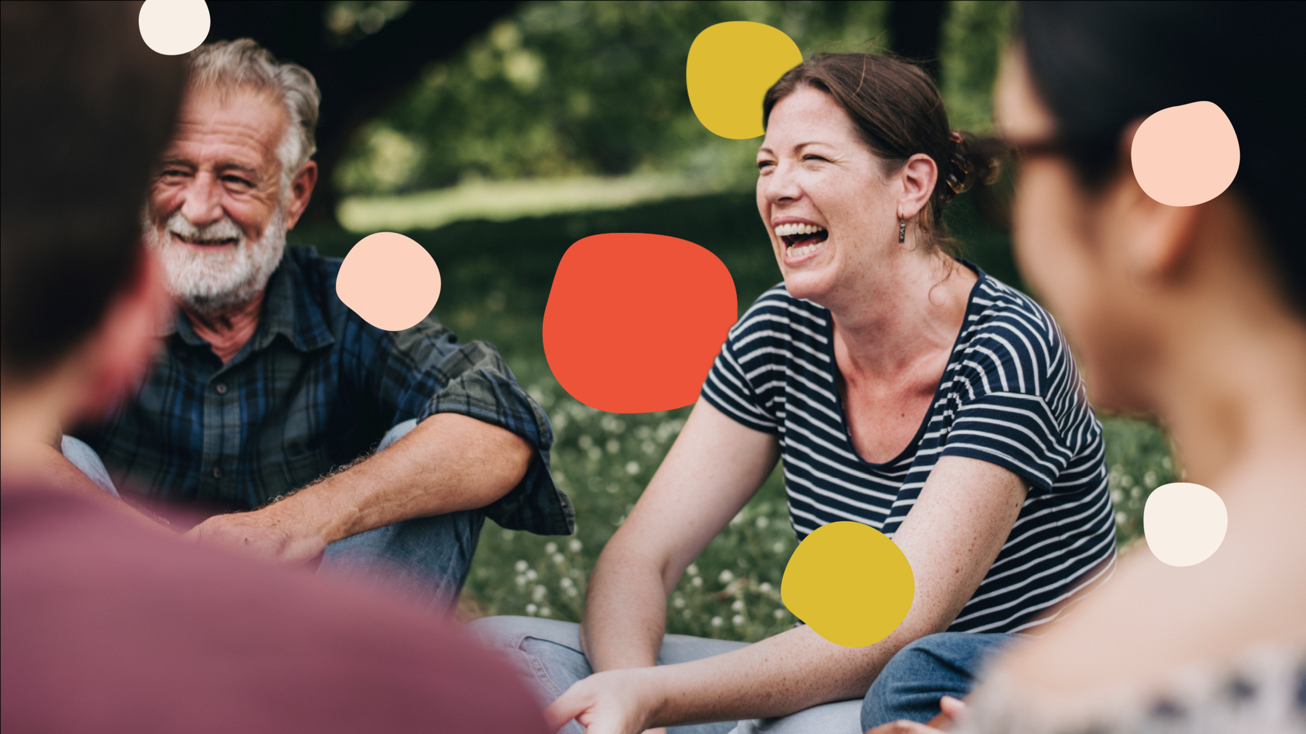 An image of a group of people sitting in a park in discussion smiling, with different colored dots, representing Talking Points, floating amongst them.
