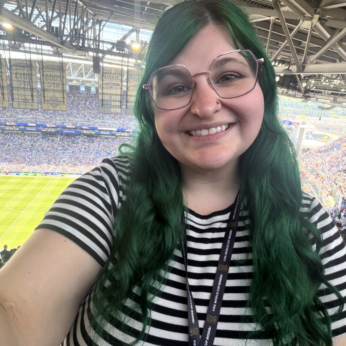 Young woman with glasses sitting in the stadium at a professional soccer game.