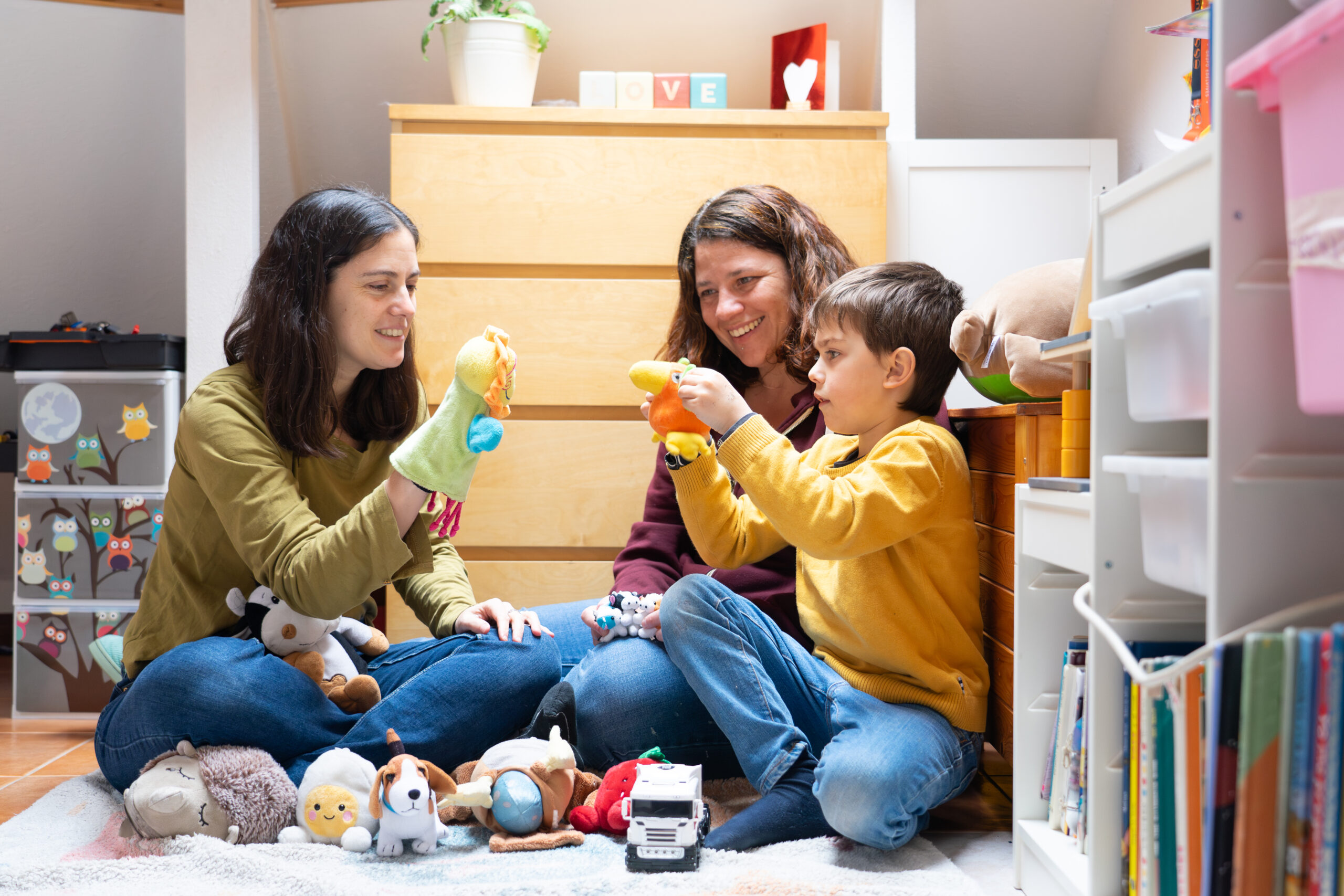 A family and therapist play together in the room with child's toys.