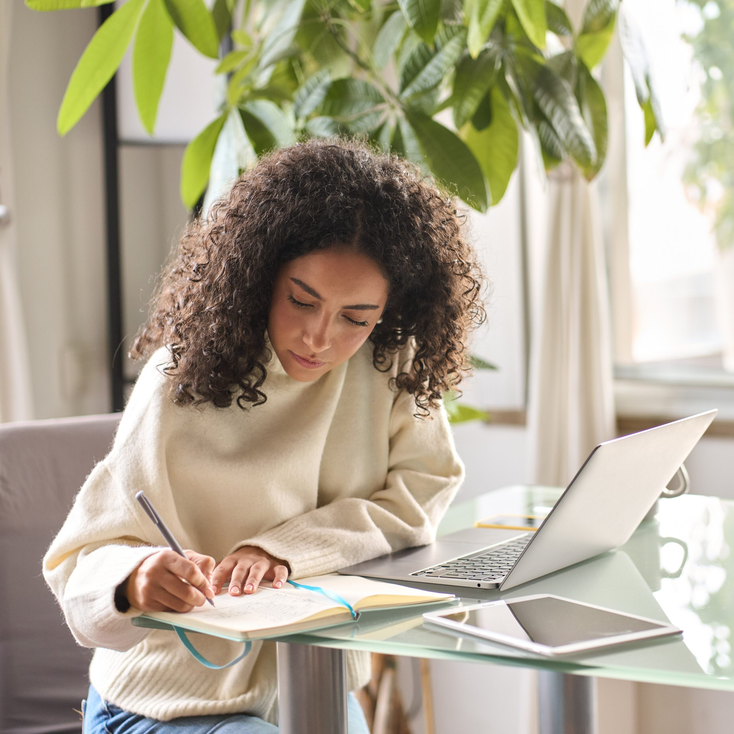 Young woman student using laptop watching online webinar writing at home. Young woman, girl student using laptop elearning or remote working at home office using laptop pc computer for webinar, learning online training digital education sitting at table, writing notes.