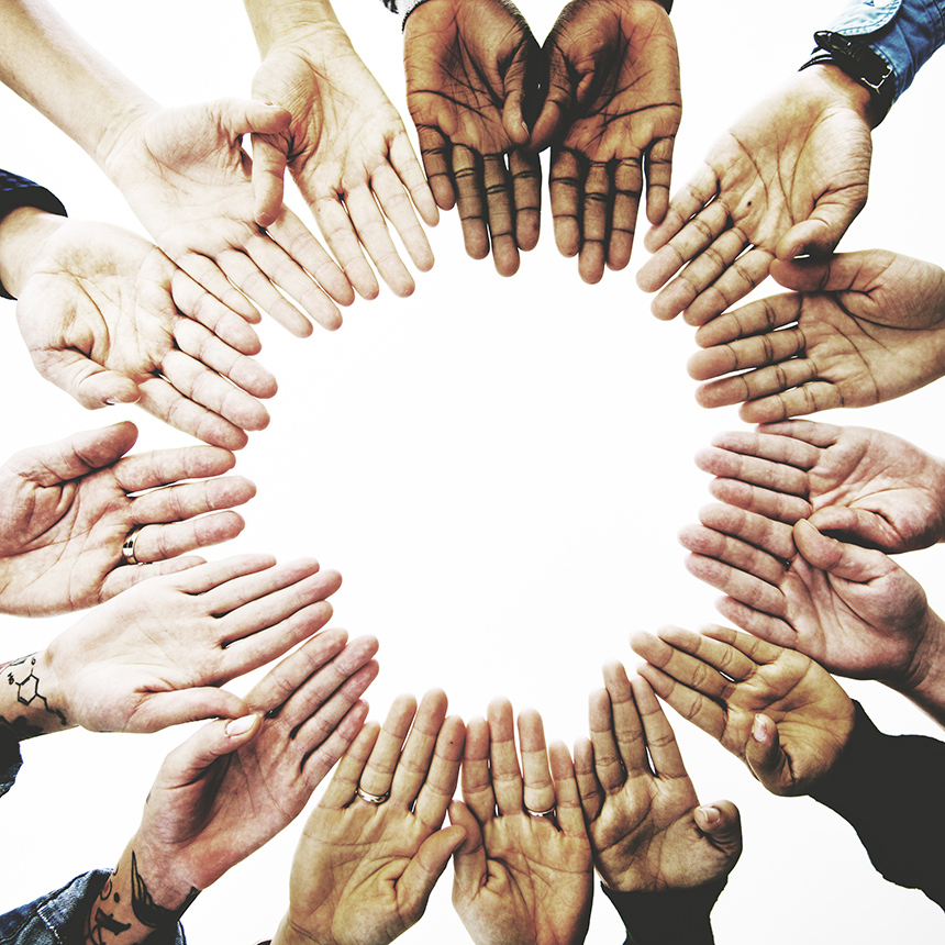 Hands in a diverse assortment of skin tones coming together in a circle.