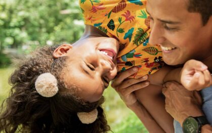 Father with daughter on shoulders playing and laughing.