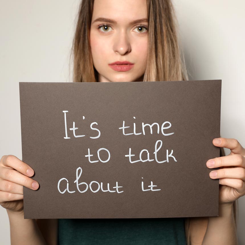 Woman holding a sign that reads, "It's time to talk about it."